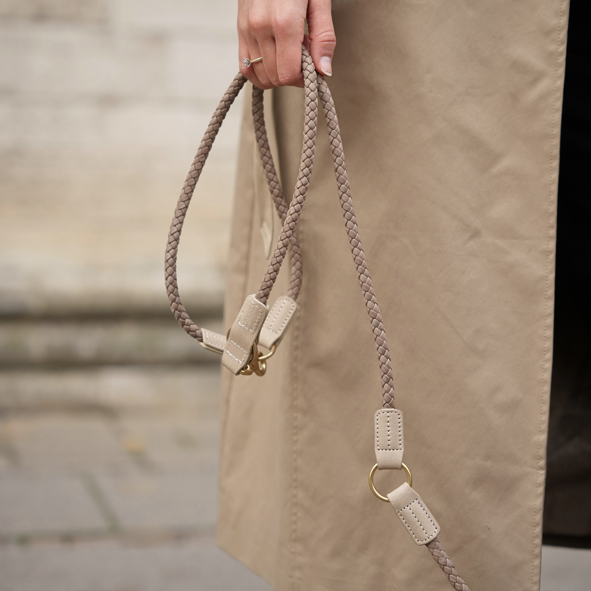 Hand holding a braided rope dog leash with leather details