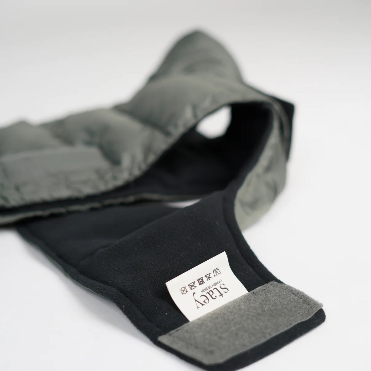 The moss green quilted dog coat laid flat, showing its lining and Staey label