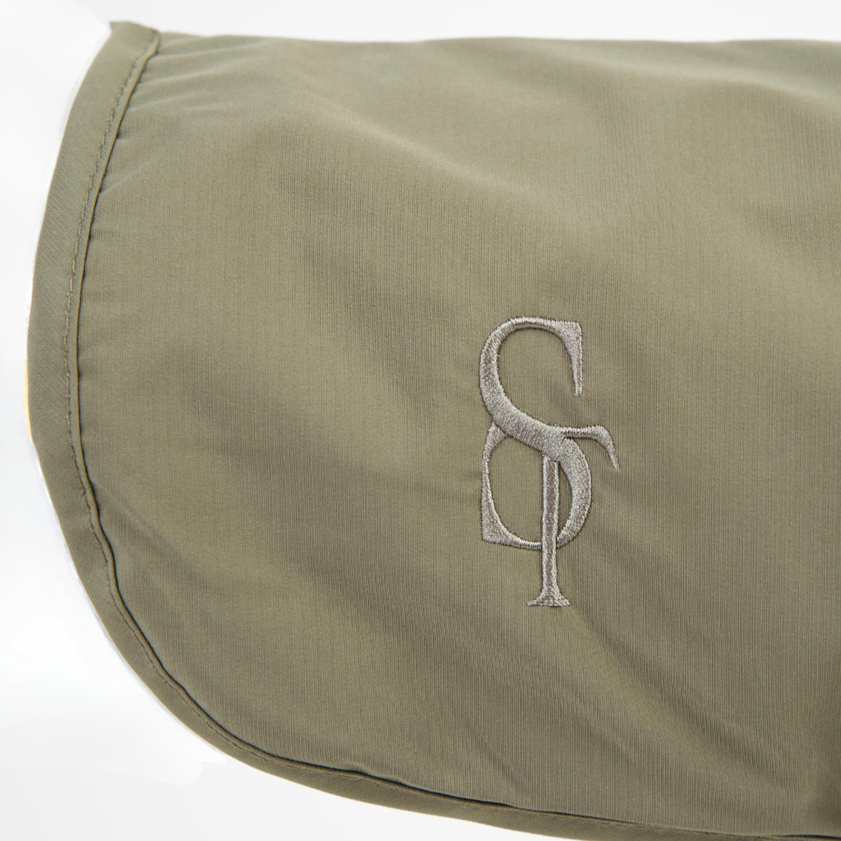 Close-up of the embossed Staey monogram on the moss green rain coat