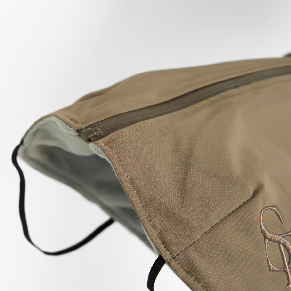 The taupe rain coat with harness laid flat, showing the Staey monogram