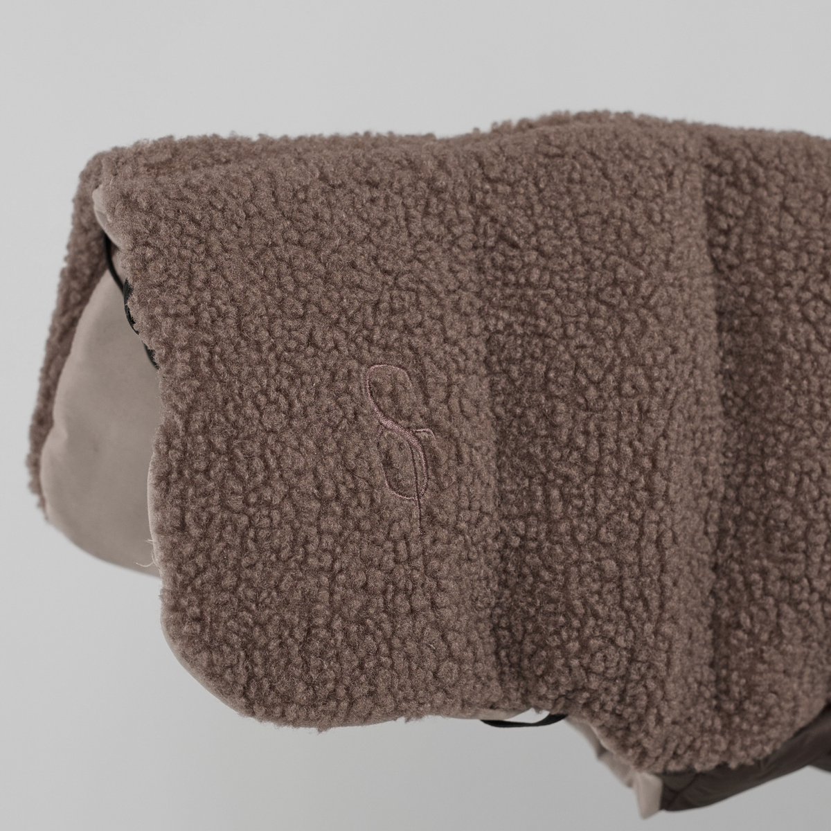 Gros plan sur le monogramme Staey en relief sur le manteau pour chien en peluche Taupe