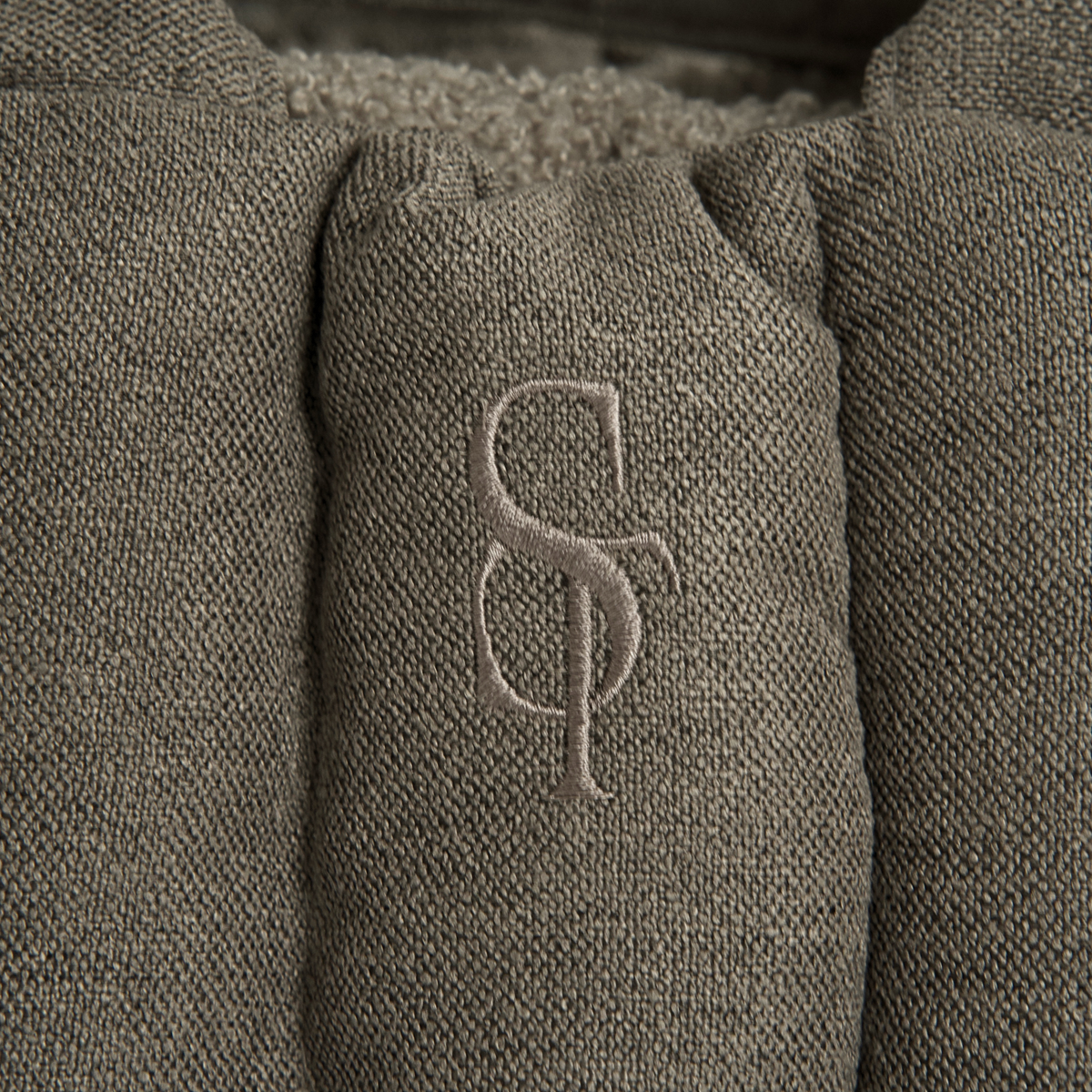 Close-up of the embossed Staey monogram on the olive teddy carrier bag