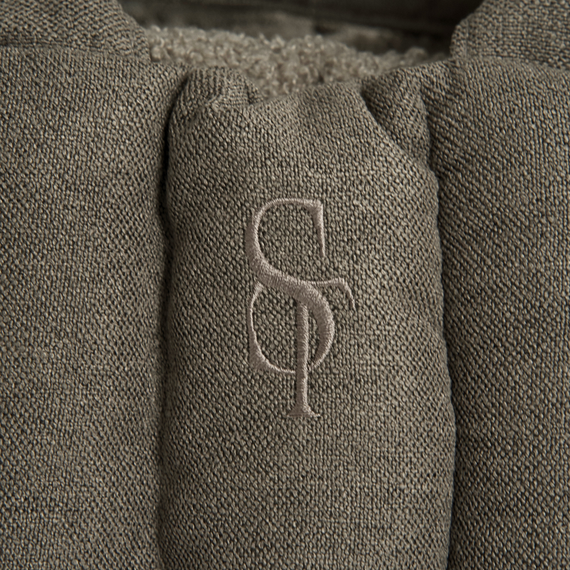 Close-up of the embossed Staey monogram on the olive teddy carrier bag
