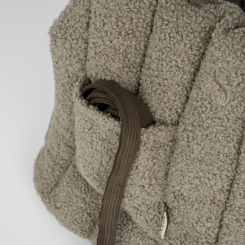 Close-up of the zip and side pocket on the olive teddy carrier bag